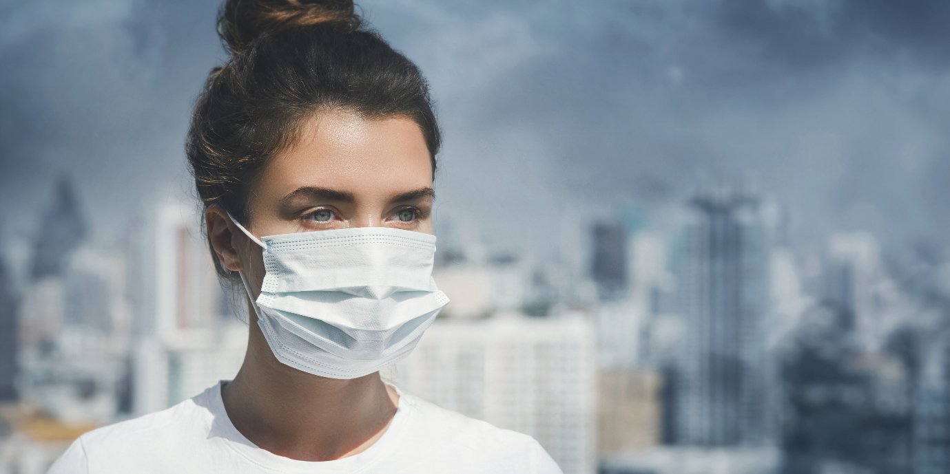 Women wearing a face mask to protect her from the air pollution happening in the background