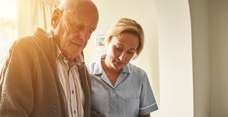 senior man and carer guiding him as he walks