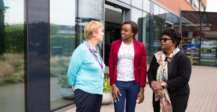 Three women standing outside a hospital talking