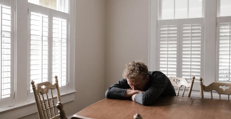 Man with head on table in distress