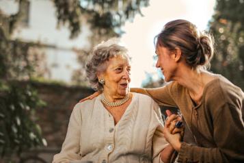 Adult smiling with older mother outside