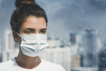 Women wearing a face mask to protect her from the air pollution happening in the background