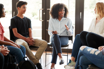 group of young people sitting on chairs in a circle having a conversation