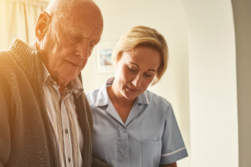 senior man and carer guiding him as he walks