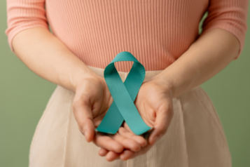 women with her hand together in front with a blue ribbon for cancer awareness in her hands