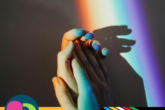 hands holding with a rainbow reflection on them